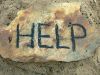 Help message on a rock in the middle of the beach, written with ashes